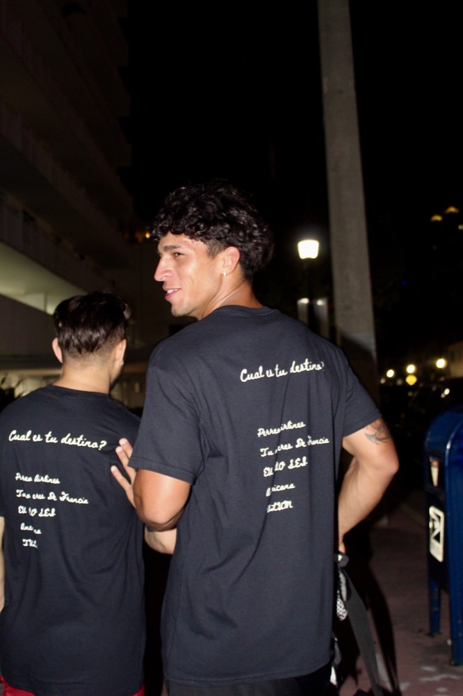 Cual Es Tu Destino merch worn by two people